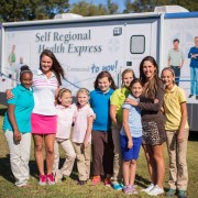Symetra Tour players Stefanie Kenoyer (left) and JayeMarie Green (right) visit with local students (from left) Shamiya Moraieune, Katie Kellum, Summer Karle, Jennings Brasier, Dru Strickland, Clary Pederson and Collins Strickland featuring the Self Regional Health Express. The Self Regional Healthcare Foundation Women's Health Classic will benefit women's health initiatives in the Lakelands, including support for the Health Express, which offers health outreach, including screenings and education.