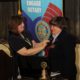 Lorraine Angelino of Greenwood is installed as the new Rotary District Governor during a special event held at Piedmont Technical College in June. Here, she receives a pin from Kim Gramling, the immediate past District Governor, who is from Seneca.