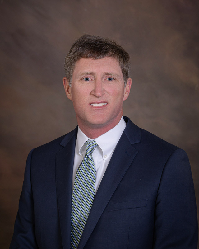 Professional headshot of a male healthcare administrator in business attire