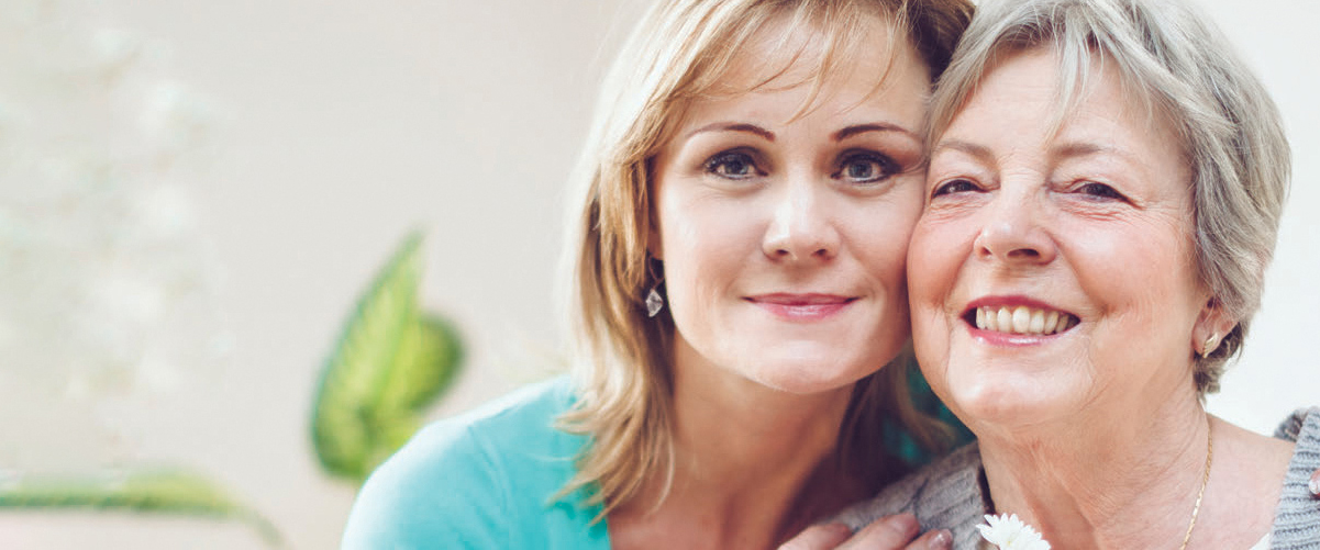 Two women, affectionately pressing their heads together and smiling at the camera