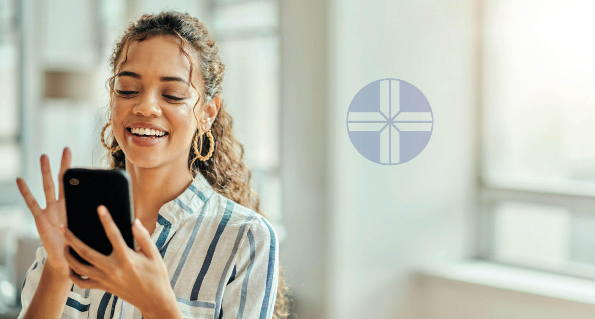 Woman smiling while using smartphone in bright healthcare facility interior