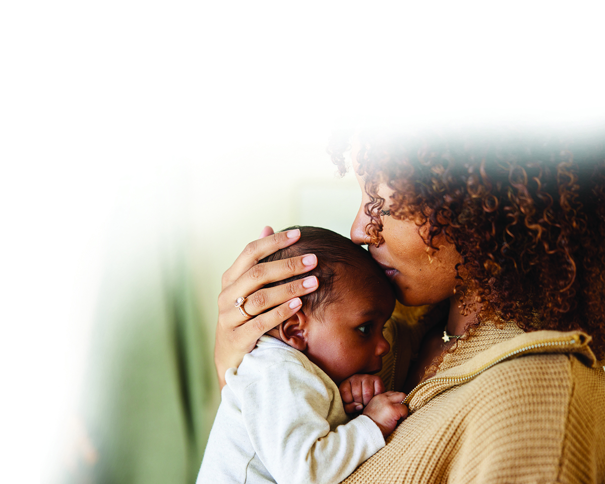 Mother holding and kissing infant baby in tender healthcare moment
