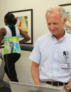 Healthcare provider speaking with patient wearing athletic attire in clinical setting.