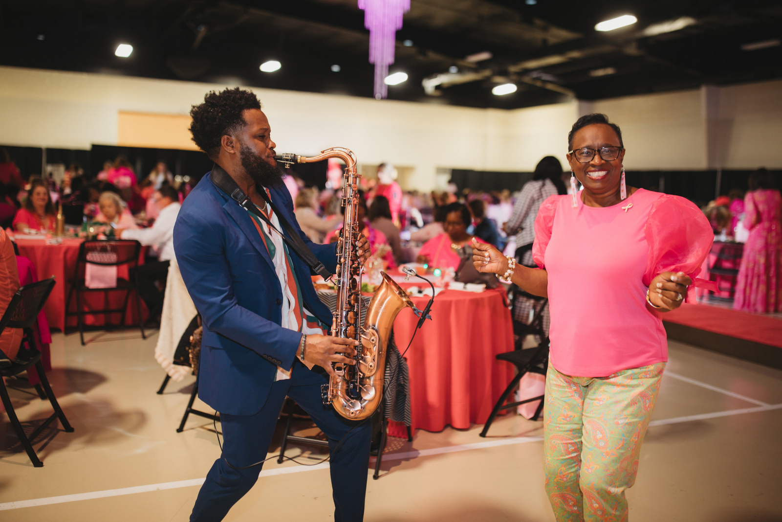 Saxophone player performing at community health event with seated attendees