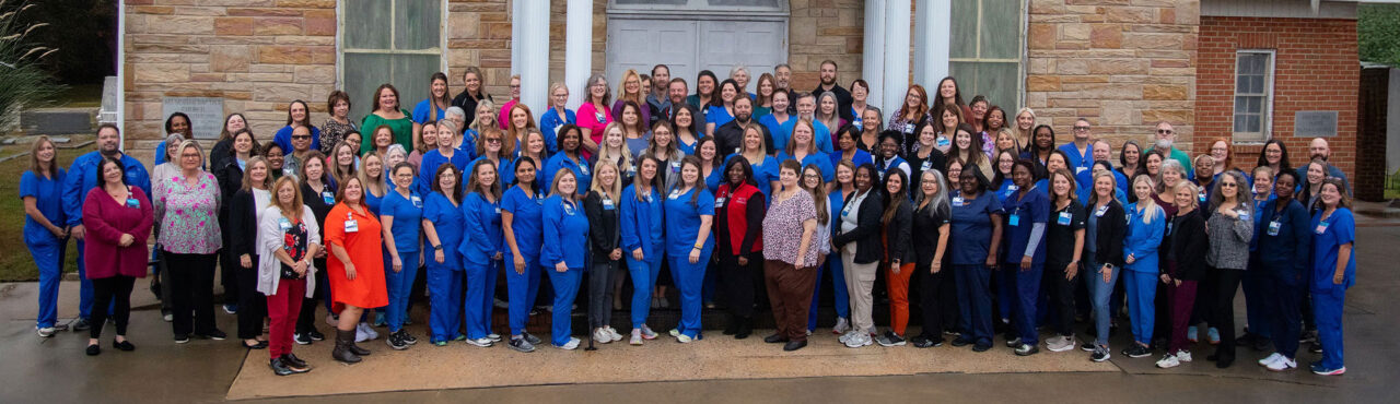 Large group of Self Regional Healthcare staff members posing together outside a brick building.