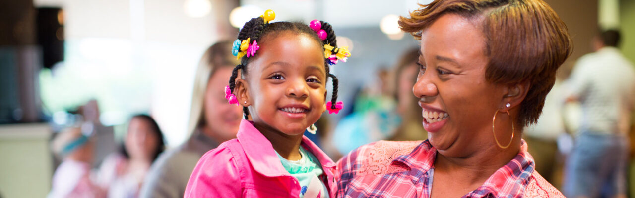 Adult and child smiling together at a healthcare community event or clinic visit.