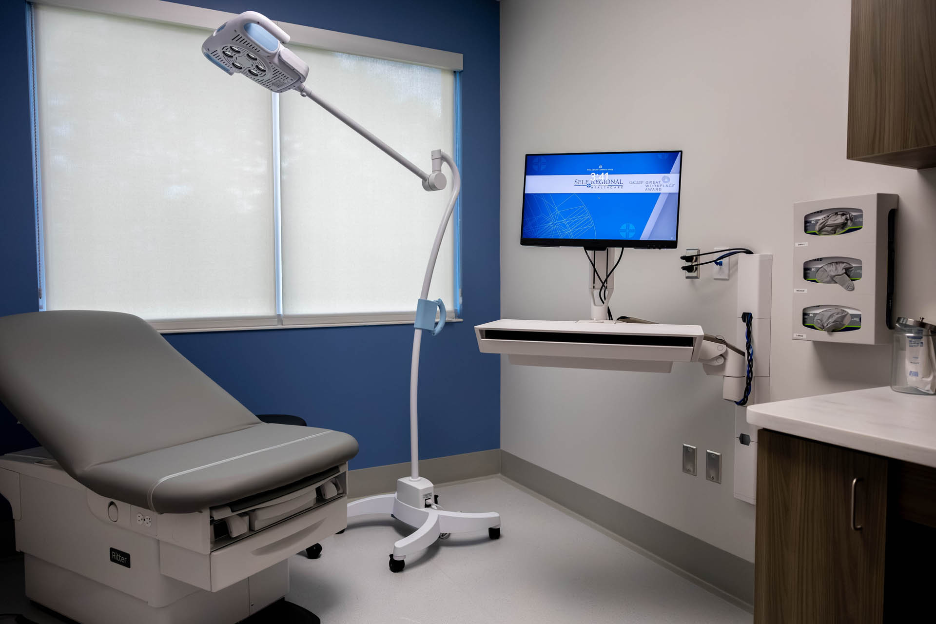 Additional examination room with exam table, patient monitor, exam light, and glove station