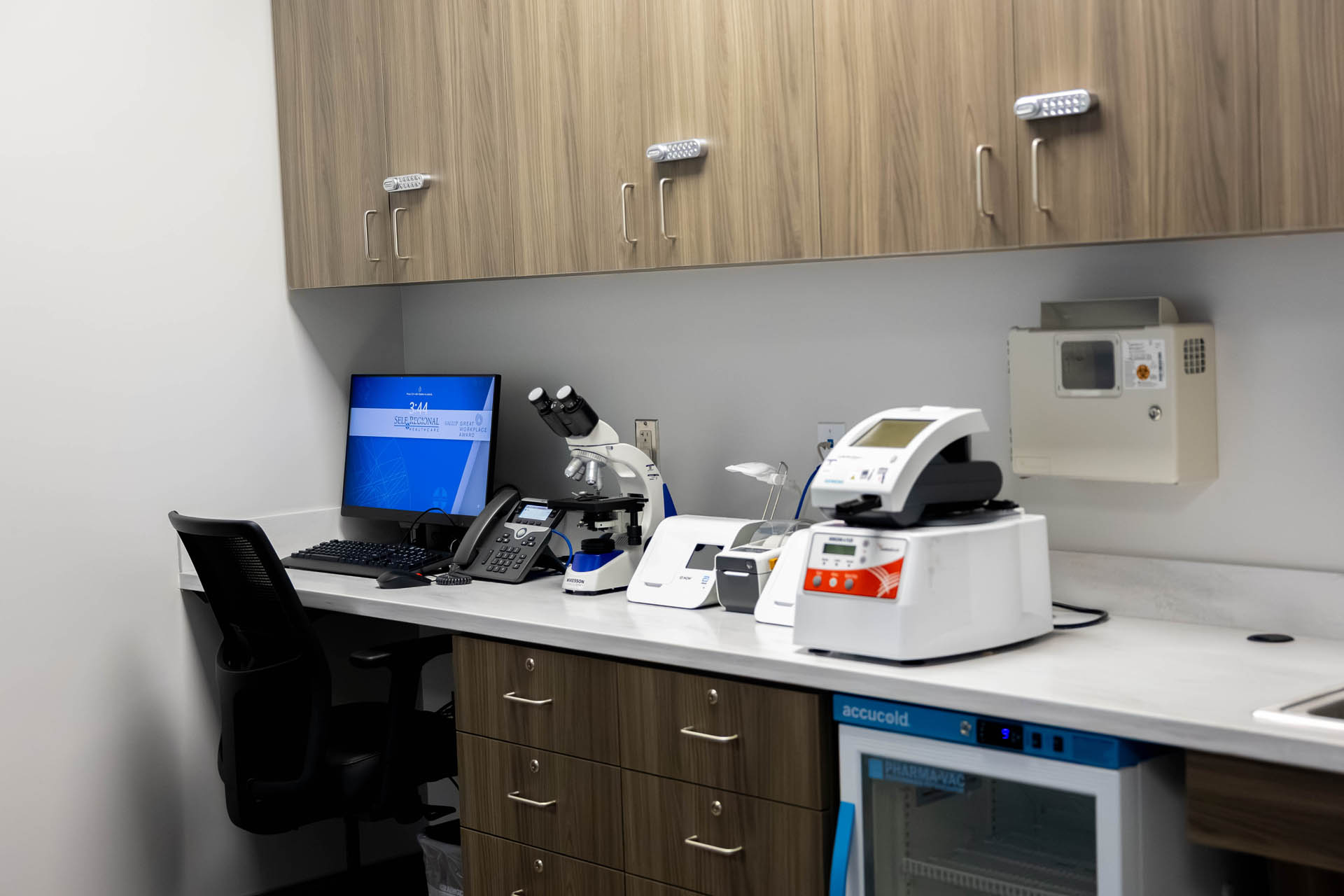 In-clinic laboratory workstation with microscope, sample testing equipment, and pharmacy-grade refrigerator