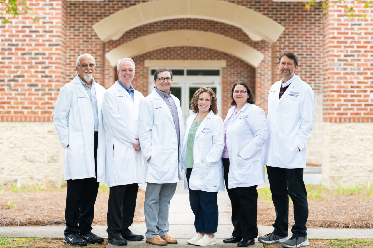 Six Family Healthcare Tower Pointe providers in white coats standing outside the practice entrance